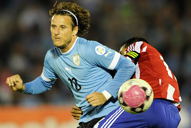 Diego Forlán forceja con el paraguayo Paulo Da Silva, le pelota sigue de largo.