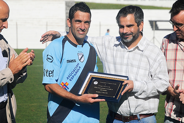 Diego Perrone recibe la plaqueta reconociemiento de manos del presidente Oscar Curuchet.