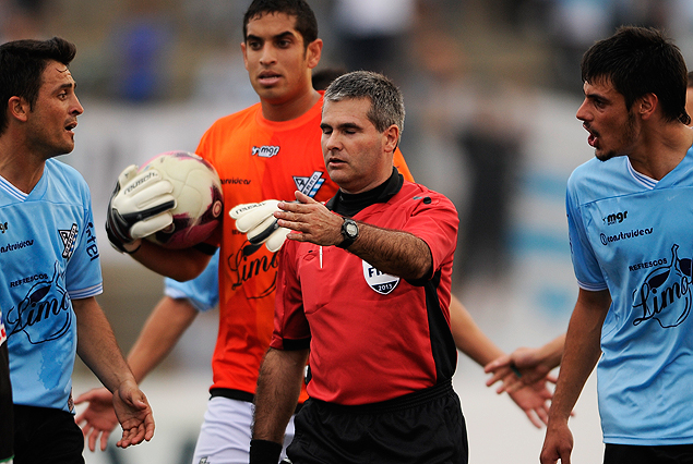 El primer asistente Marcelo Costa rodeado por jugadores de Cerro en el reclamo tras la convalidación del segundo gol de El Tanque.