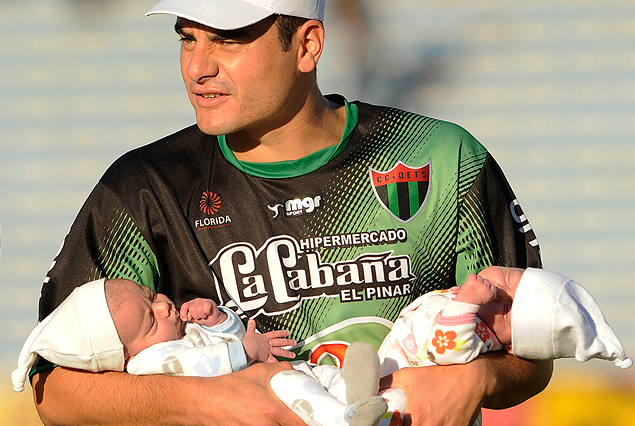 Maximiliano Lombardi con sus dos hijos en brazos en la cancha.