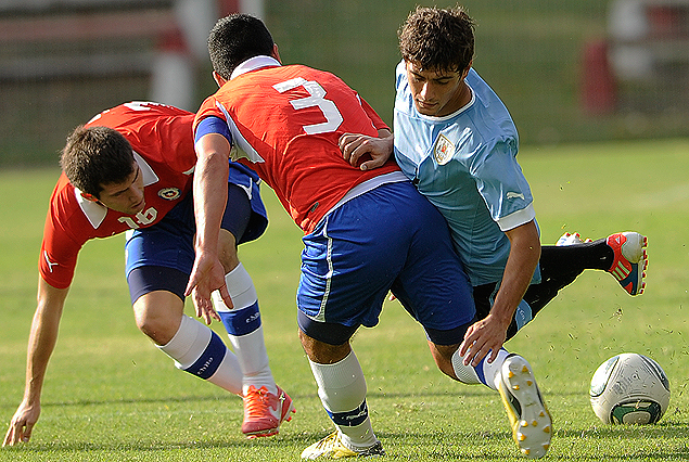 Giorgian De Arrascaeta tropieza ante la marcación del defensor chileno.