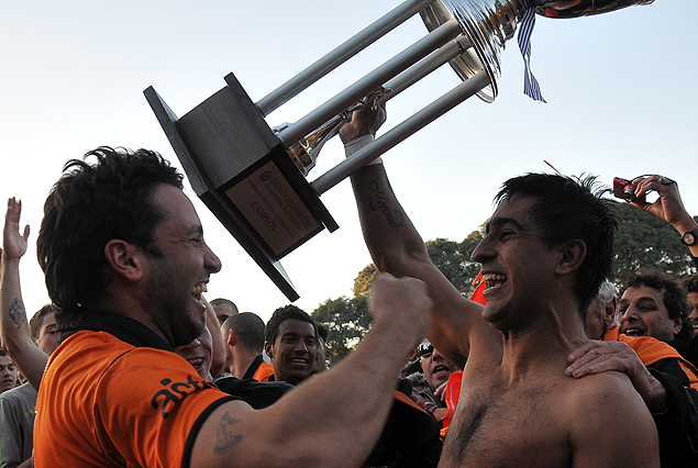 Maureen Franco, con el torso desnudo, levanta la Copa de Campeón. 