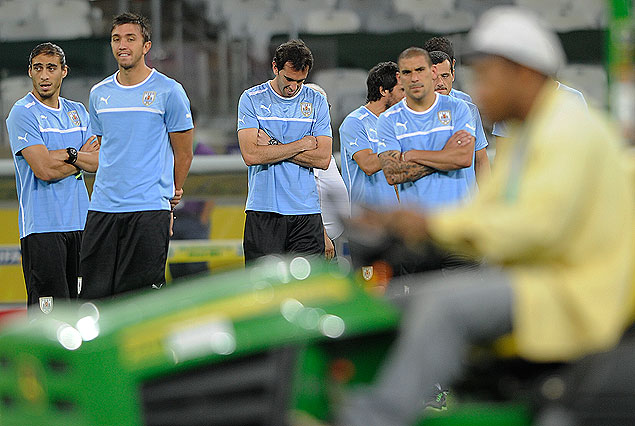 Martín Cáceres, Fernando Muslera, Diego Godín y Maxi Pereira en el campo de juego del estadio Mineirao, observan como el canchero, en un pequeño tractor, trabaja en las afueras de la cancha.  
