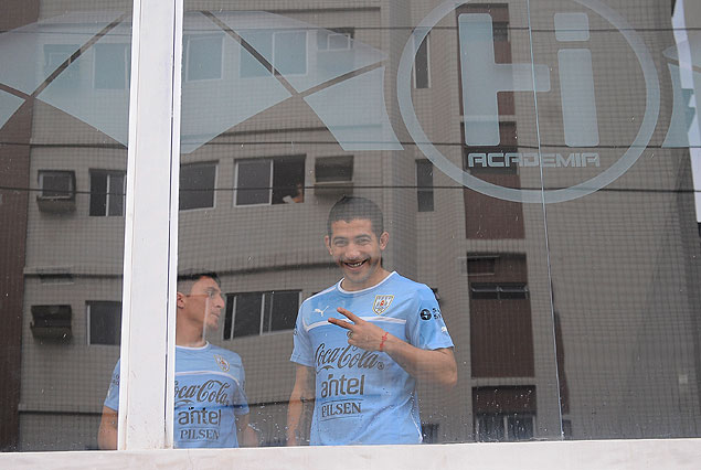 Walter Gargano, hace la "V" de la victoria, mirando hacia la calle desde el gimnasio. En el inmenso vental ase refleja el edificio que se encuentra frente a la Academia HI. 