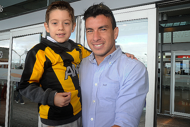 Jorge "Japo" Rodríguez y su ahijado con la camiseta de Peñarol, el domingo en el arribo del volante al Aeropuerto de Carrasco. 