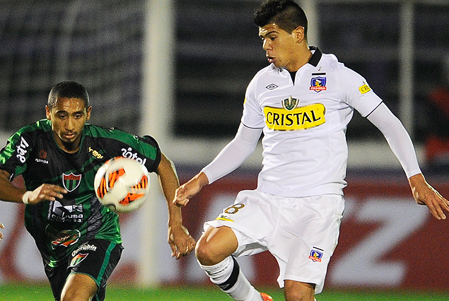 Jonathan Iglesias corre con la vista fija en el balón, el chileno Esteban Pavez intenta cruzarse en su camino. 