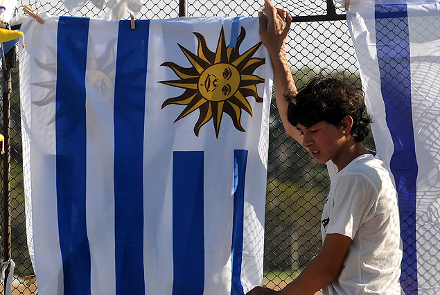 Un hincha uruguayo con vestimenta típica de verano junto a la bandera uruguaya. 