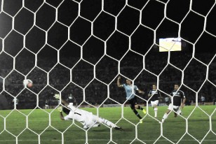 Edinson Cavani ya sacó el remate, la pelota supera el esfuerzo final del arquero argentino Sergio Romero y viaja con destino de red. Tercer gol uruguayo.