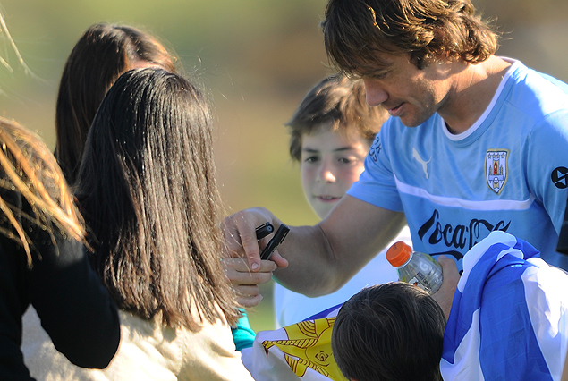 El capitán Diego Lugano, rodeado de niños y firmando autógrafos, al finalizar el entrenamiento del lunes por la tarde de la selección uruguaya.