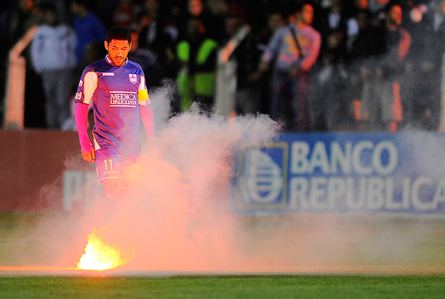 Nicolás Olivera iluminado por una de las bengalas encendidas que cayeron en pleno campo de juego.