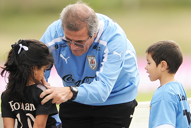 Oscar Tabárez rodeado por niños en el complejo. El Maestro deja su firma en la camiseta de una pequeña.