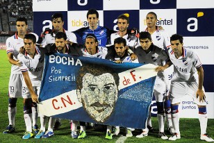 Los jugadores de Nacional posando con la bandera con caricatura y leyenda, "Bocha por siempre".