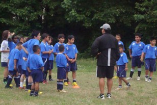 El profesor de educación física en plena tarea de enseñanza de fútbol a los niños.