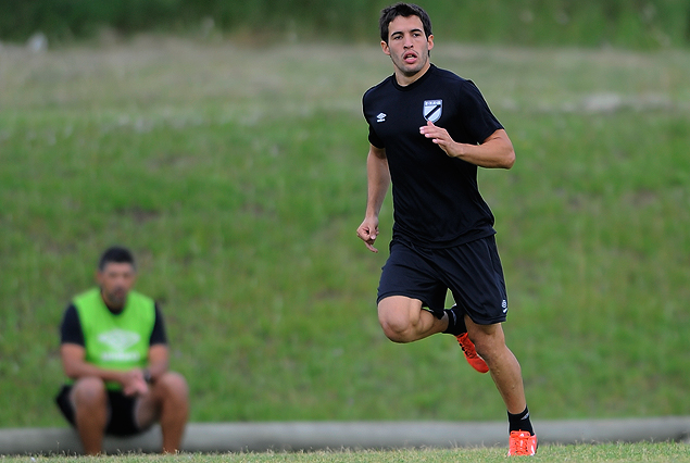 Camilo Mayada corre en primer plano en la práctica de fútbol, seguido a lo lejos por el entrenador Leonardo Ramos. 