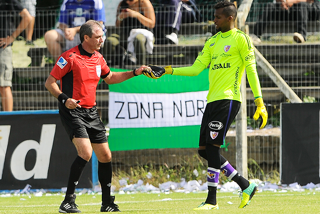 Momento de preocupación. Martin Vázquez y Luis Mejía con una piedra que cayó desde la tribuna de Racing. Estuvo cerca la suspensión del encuentro. 