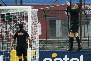 Yimmi Alvarez, el cuarto árbitro, parado sobre la publicidad estática, soluciona la caída de la red del arco de la Amsterdam.