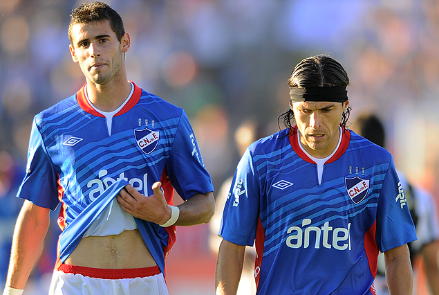 Gastón Pereiro y Alexander Medina, luciendo la nueva camiseta azul, se retiran cabizbajos de la cancha. 