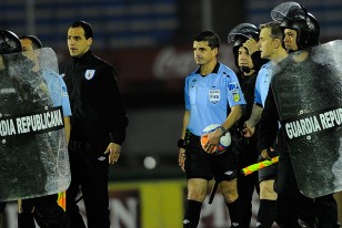 Los árbitros dejan la cancha custodiados por la policía.