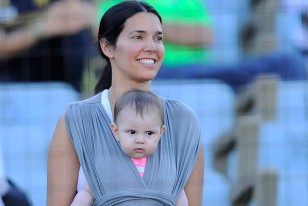 La señora de Paolo Montero, Patricia portando a su pequeña hija, de pie en la platea.
