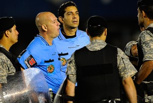 El árbitro Lopes conversa con las fuerzas policiales tras  suspender el juego por el lanzamiento de una bomba de gas lacrimógena. 
