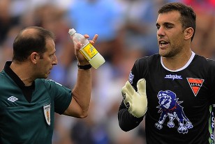 El árbitro Pablo Giménez  muestra la botella lanzada por un parcial de Nacional a la cancha y que cayó muy cerca del arquero Javier Irazún.